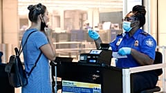 L'agent de la TSA Patrisa Johnson, à droite, aide un voyageur à passer la sécurité avant de s'envoler de Love Field à Dallas, le mercredi 24 juin 2020.