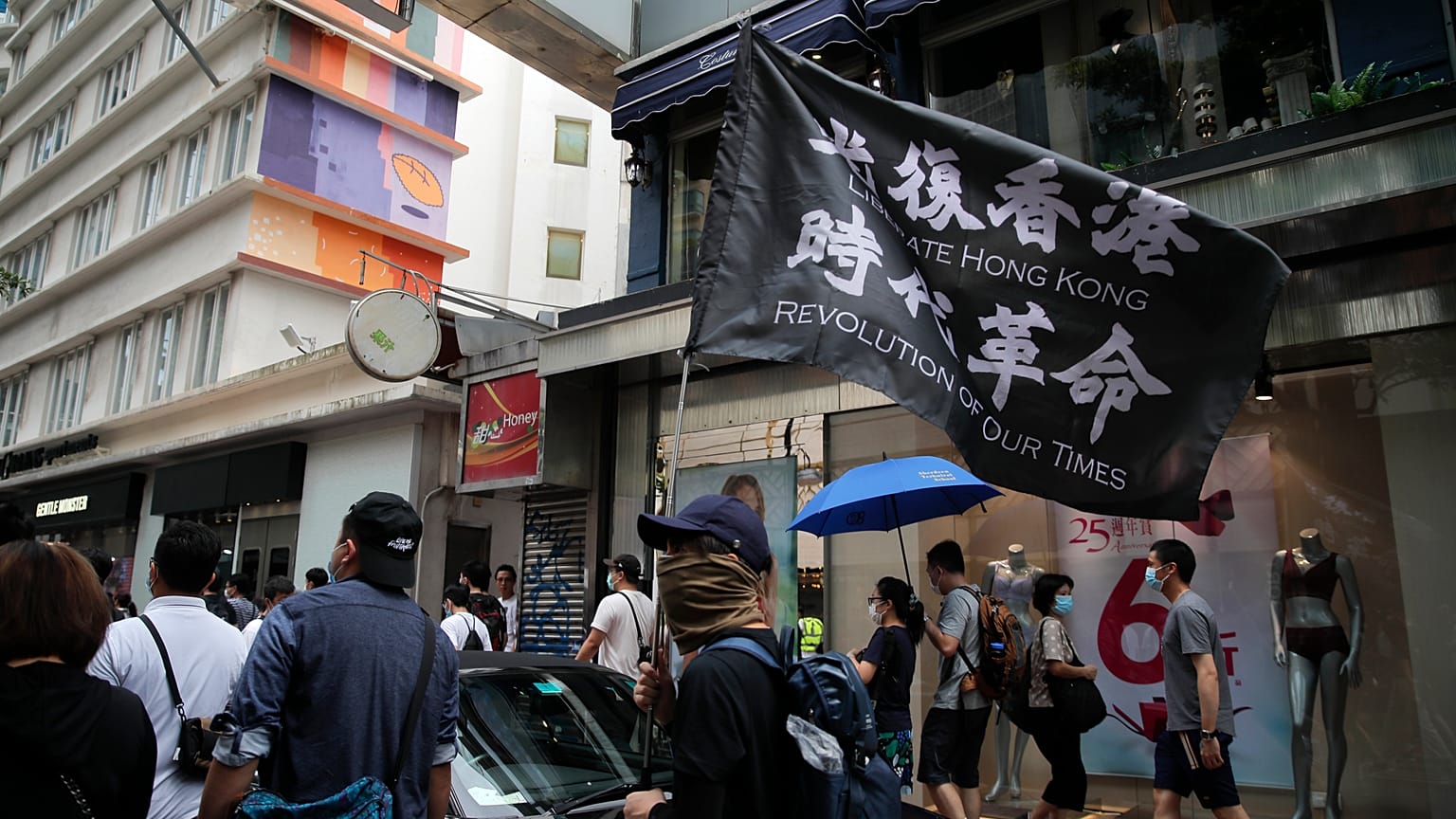 Demonstrant mit Flagge, auf der zur Befreiung Hongkongs aufgerufen wird