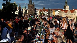 Residents sit to dine on a 500 meter long table set on the medieval Charles Bridge in Prague, Czech Republic, Tuesday, June 30, 2020.
