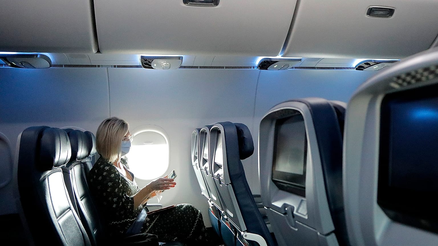 A woman uses a sanitising wipe while setting into her seat on a flight in the US