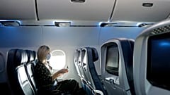 A woman uses a sanitising wipe while setting into her seat on a flight in the US