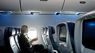 A woman uses a sanitising wipe while setting into her seat on a flight in the US