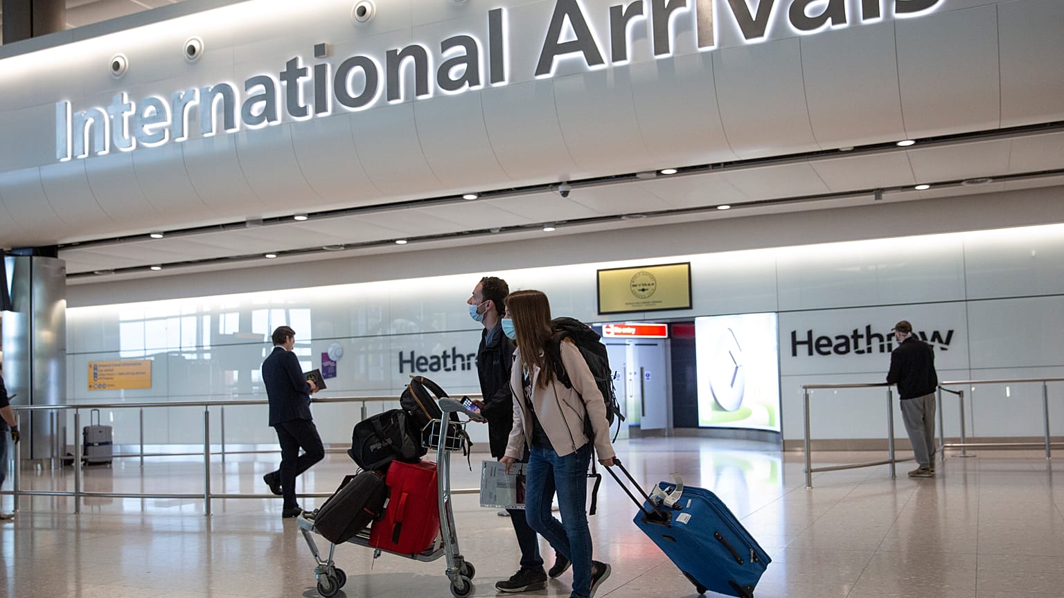 Passengers wearing face masks arrive at London's Heathrow Airport on June 8, 2020.