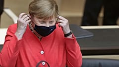 German Chancellor Angela Merkel adjusts her face mask