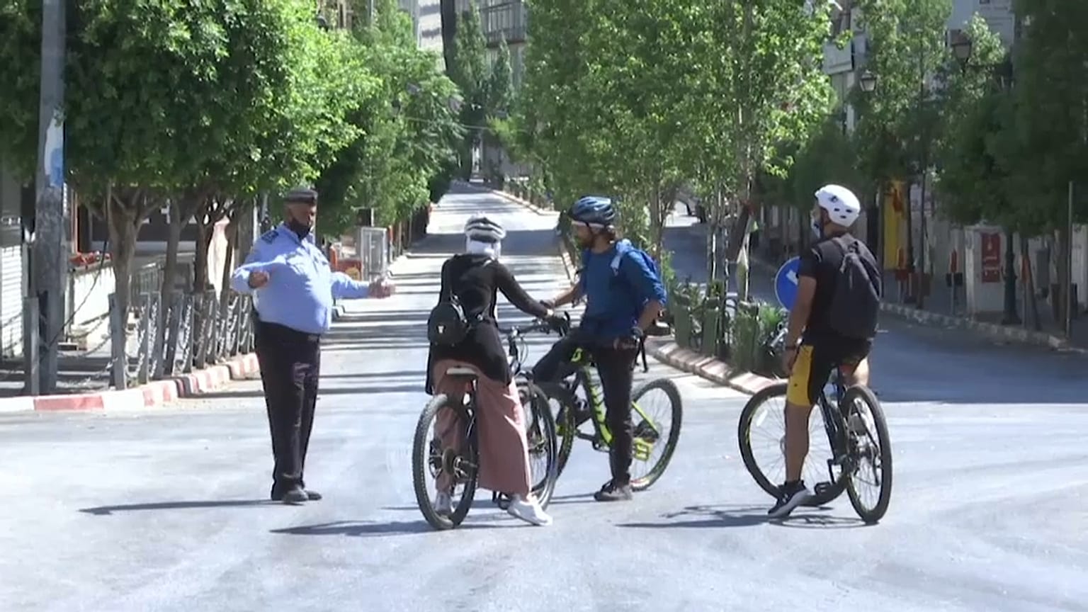 شرطي فلسطيني يتحدث مع مستعملي دراجات هوائية في رام الله - 2020/07/03