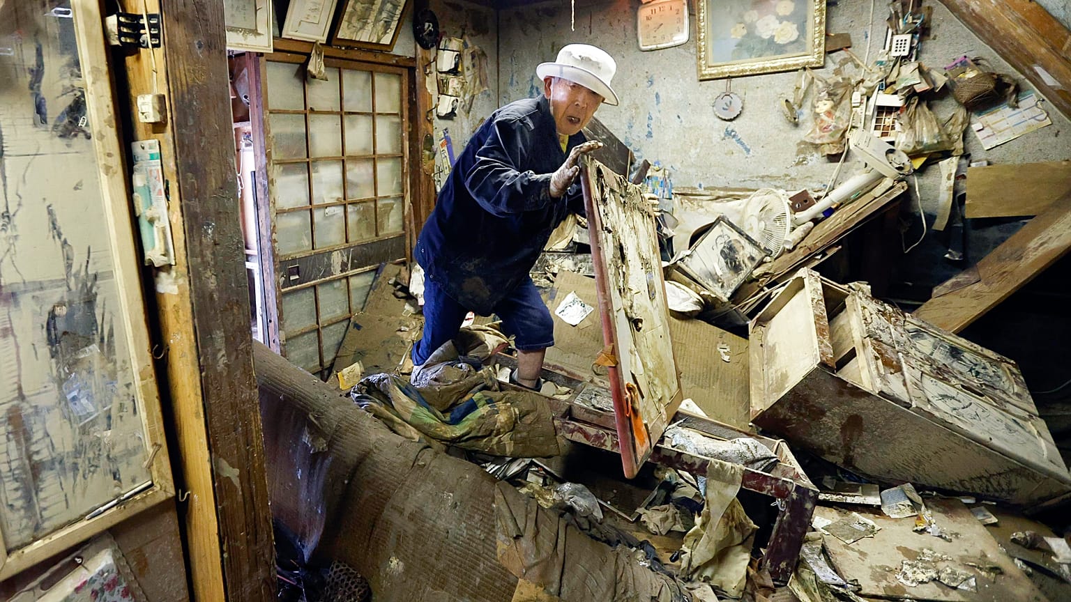 A man looks for his medicine at the house damaged by floods provoked by heavy rains in Hitoyoshi, Kumamoto prefecture, southern Japan. July 12, 2020