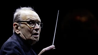 In this file photo dated Tuesday, March 6, 2018, Italian composer Ennio Morricone directs an ensemble during a concert of his "60 Year Of Music World Tour", in Milan, Italy