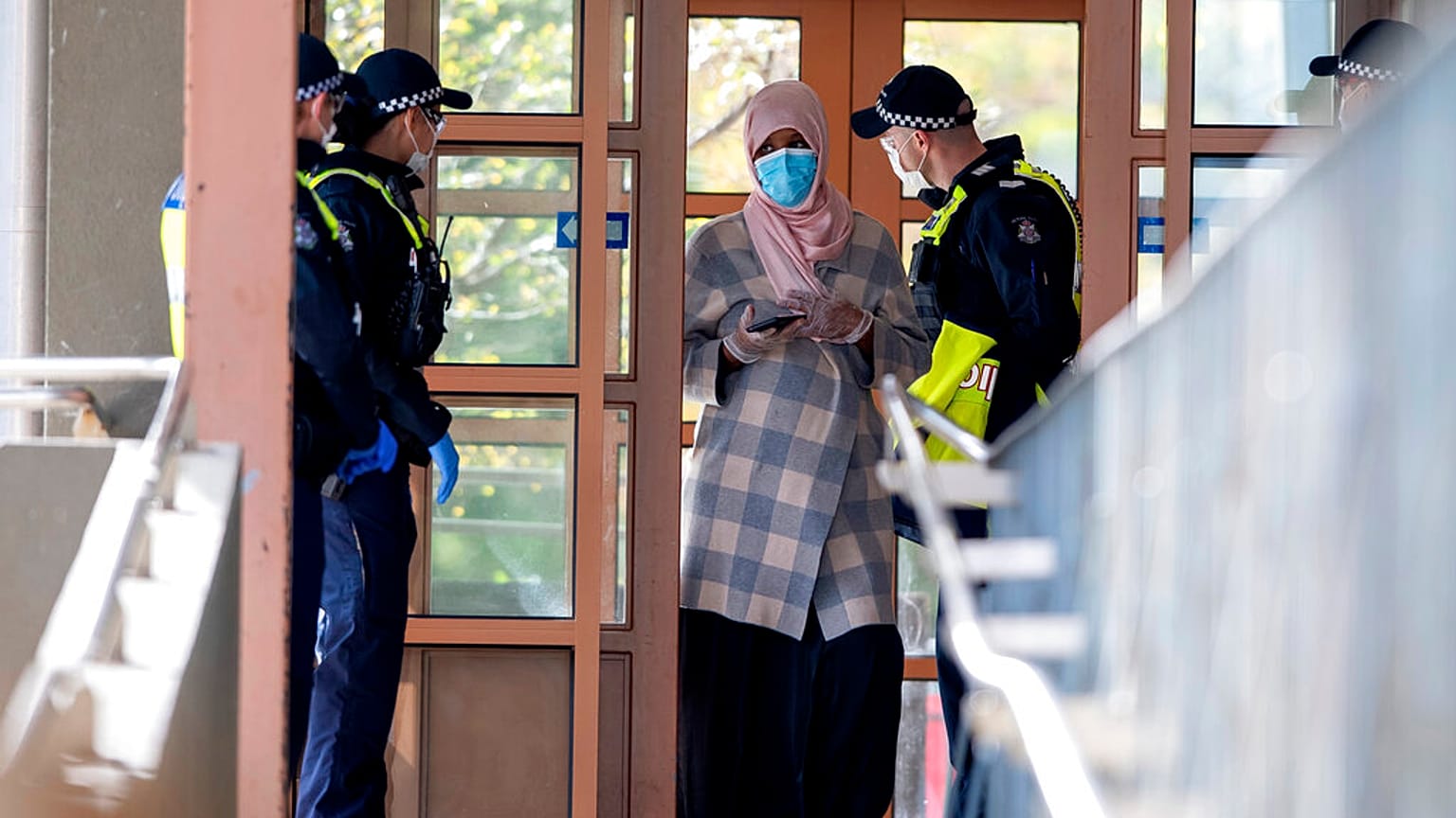 Polícia fala com uma residente de um complexo de apartamentos em confinamento em Melbourne