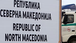 FILE - A truck driver waits behind a road sign at North Macedonia's southern border with Greece, near Gevgelija, in 2019