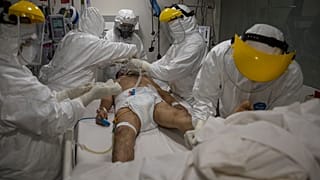 Médicos y enfermeras atienden a un paciente dentro de la unidad de cuidados intensivos para casos de COVID-19 en el hospital privado Ricardo Palma, en Lima, Perú.