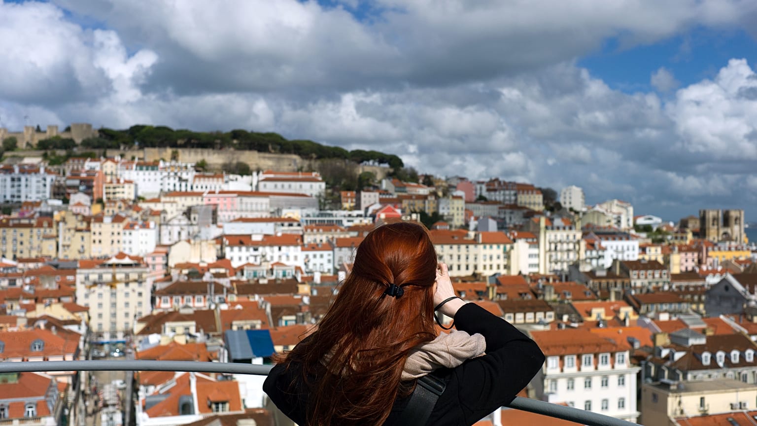 A woman takes pictures from the top of Lisbon