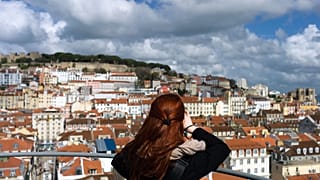 A woman takes pictures from the top of Lisbon