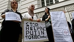 Chechen protesters hold a banner that reads "Stop helping Putin to kill Chechens" outside of the Russian embassy in Vienna on Tuesday