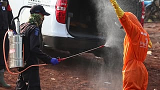 عامل يرش زميله بمطهر بعد دفن شخص مات على الأرجح بسبب كوفيد-19 في مقبرة في جاكرتا