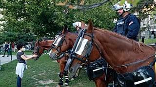 A rohamrendőrség lovát kényezteti egy járókelő Belgrádban