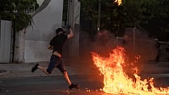 A protester throws a petrol bomb at riot police outside the Greek Parliament during a demonstration against new protest law in Athens, on Thursday July 9, 2020. 