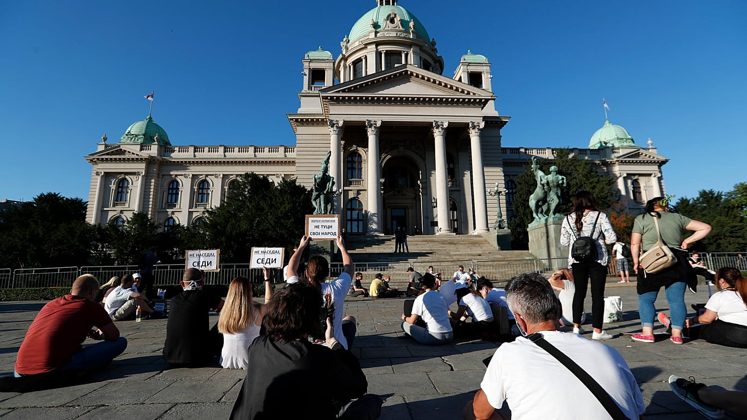 People sit during a protest in front Serbian Parliament building in Belgrade, Serbia,Thursday, July 9, 2020.