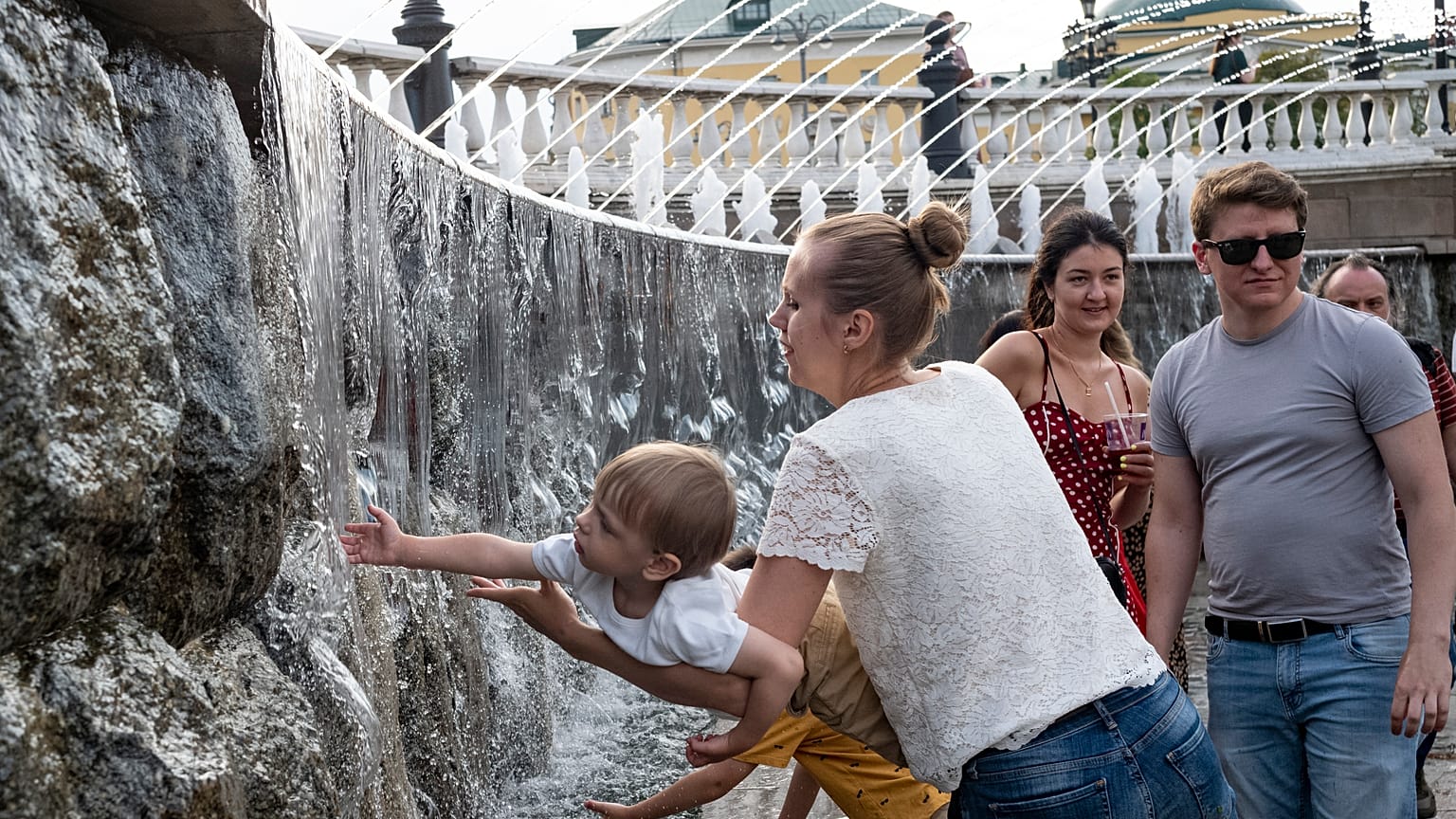 Ребенок играет с фонтаном в центре Москвы.