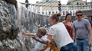 Ребенок играет с фонтаном в центре Москвы.