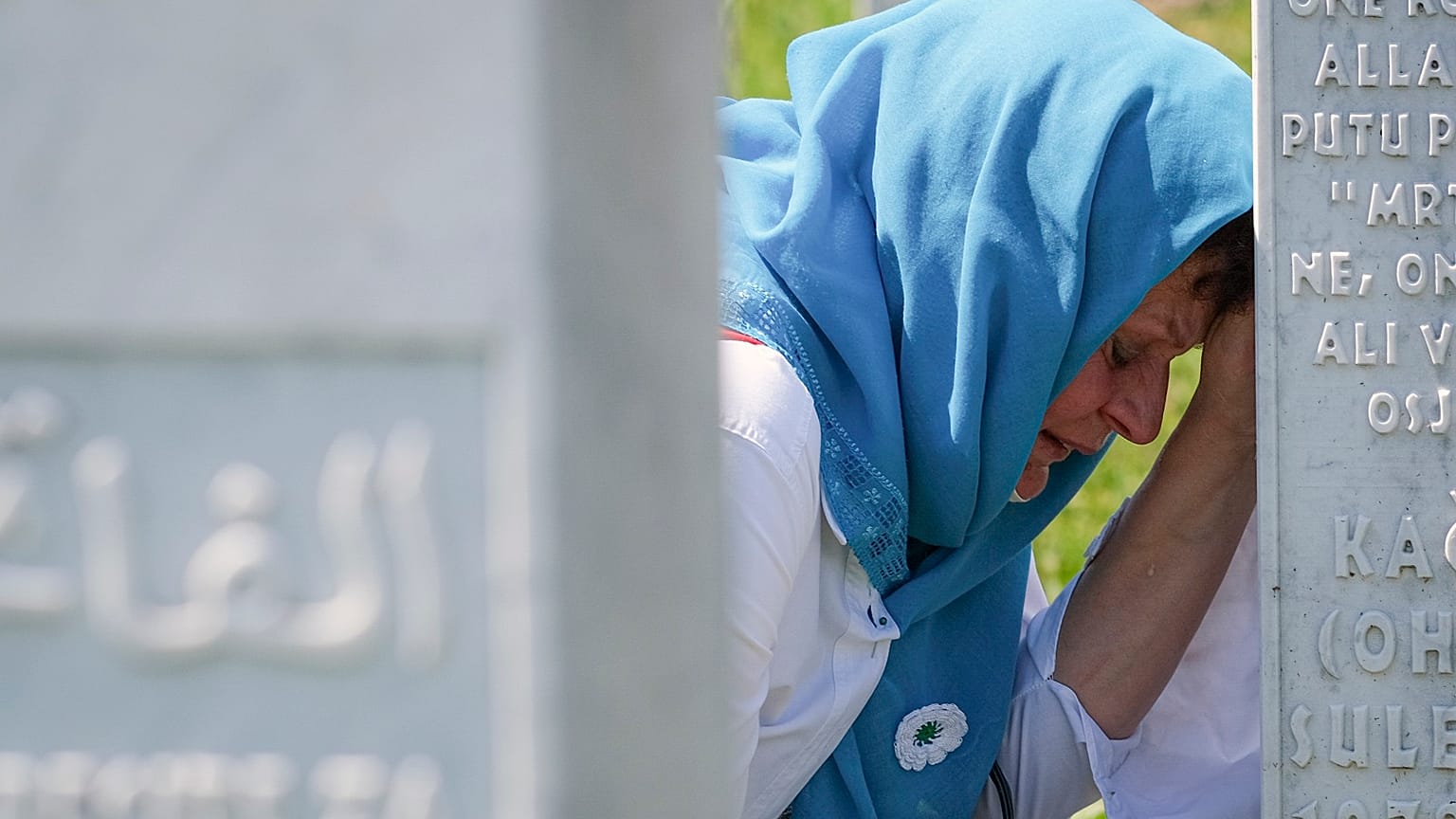 A mourner cries at the graveside of a loved one at 25th anniversary commemorations of Srebrenica.