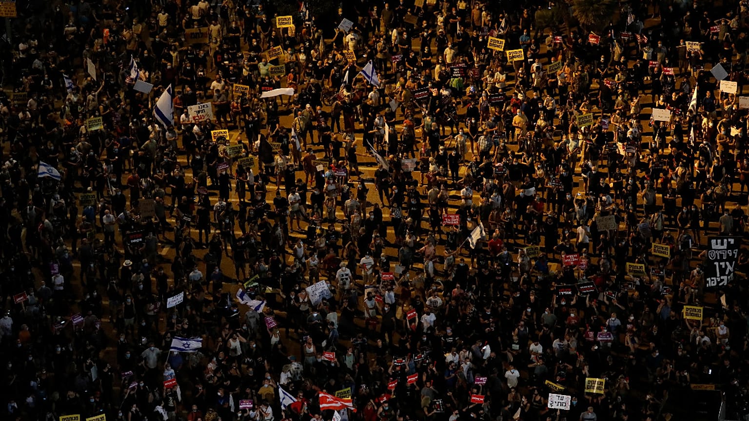 Protesters hold signs during a demonstration against Israel's government in Rabin square in Tel Aviv, Israel, Saturday, July 11, 2020.