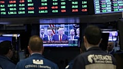 Traders listen at the New York Stock Exchange to President Donald Trump's televised speech from the White House
