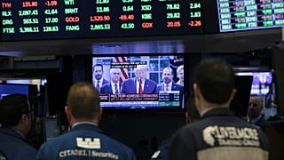 Traders listen at the New York Stock Exchange to President Donald Trump's televised speech from the White House