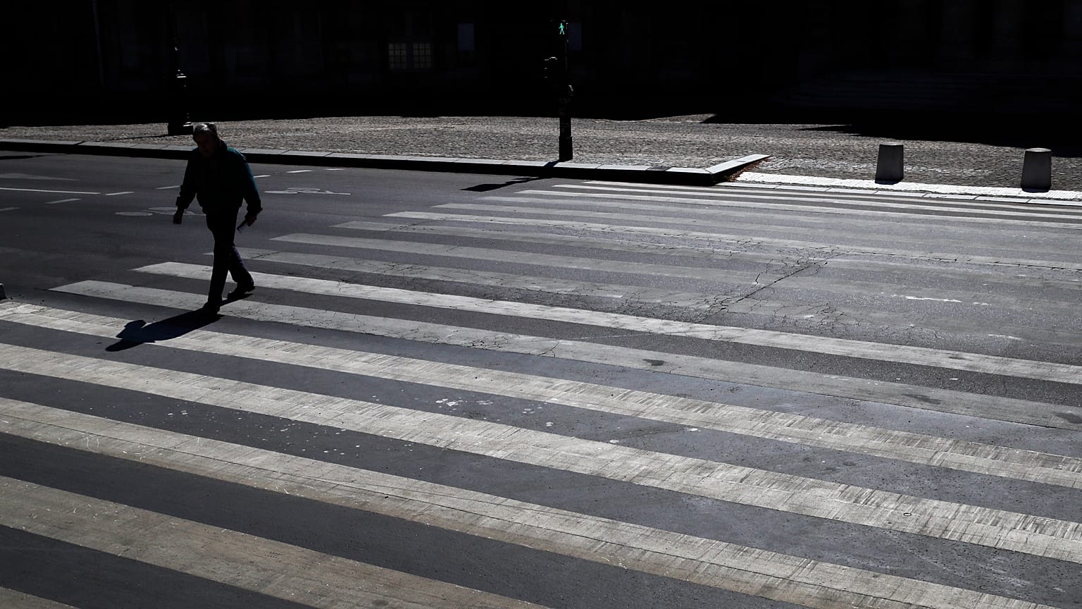 A man crosses an empty street during a nationwide confinement to counter the Covid-19, in Paris, Saturday, April 4, 2020.