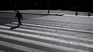 A man crosses an empty street during a nationwide confinement to counter the Covid-19, in Paris, Saturday, April 4, 2020.