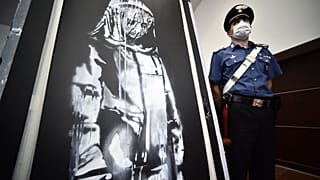 A policeman stands guard near a piece of art attributed to Banksy, that was stolen at the Bataclan in Paris in 2019