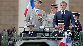 France's President Emmanuel Macron stands in the command car as he reviews troops before the start of the Bastille Day parade. 14 July, 2020.