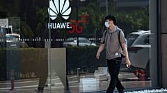 A man wearing a mask to curb the spread of the coronavirus walks past a Huawei store promoting 5G technologies in Beijing on Wednesday, July 15, 2020. 