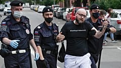 Police officers detain Kommersant newspaper journalist Alexander Chernykh, who is wearing a T-shirt with sign "Freedom to Safronov", during Monday's rally