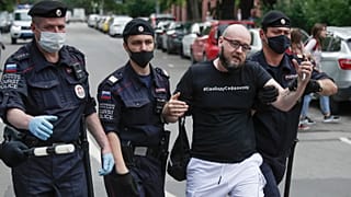 Police officers detain Kommersant newspaper journalist Alexander Chernykh, who is wearing a T-shirt with sign "Freedom to Safronov", during Monday's rally