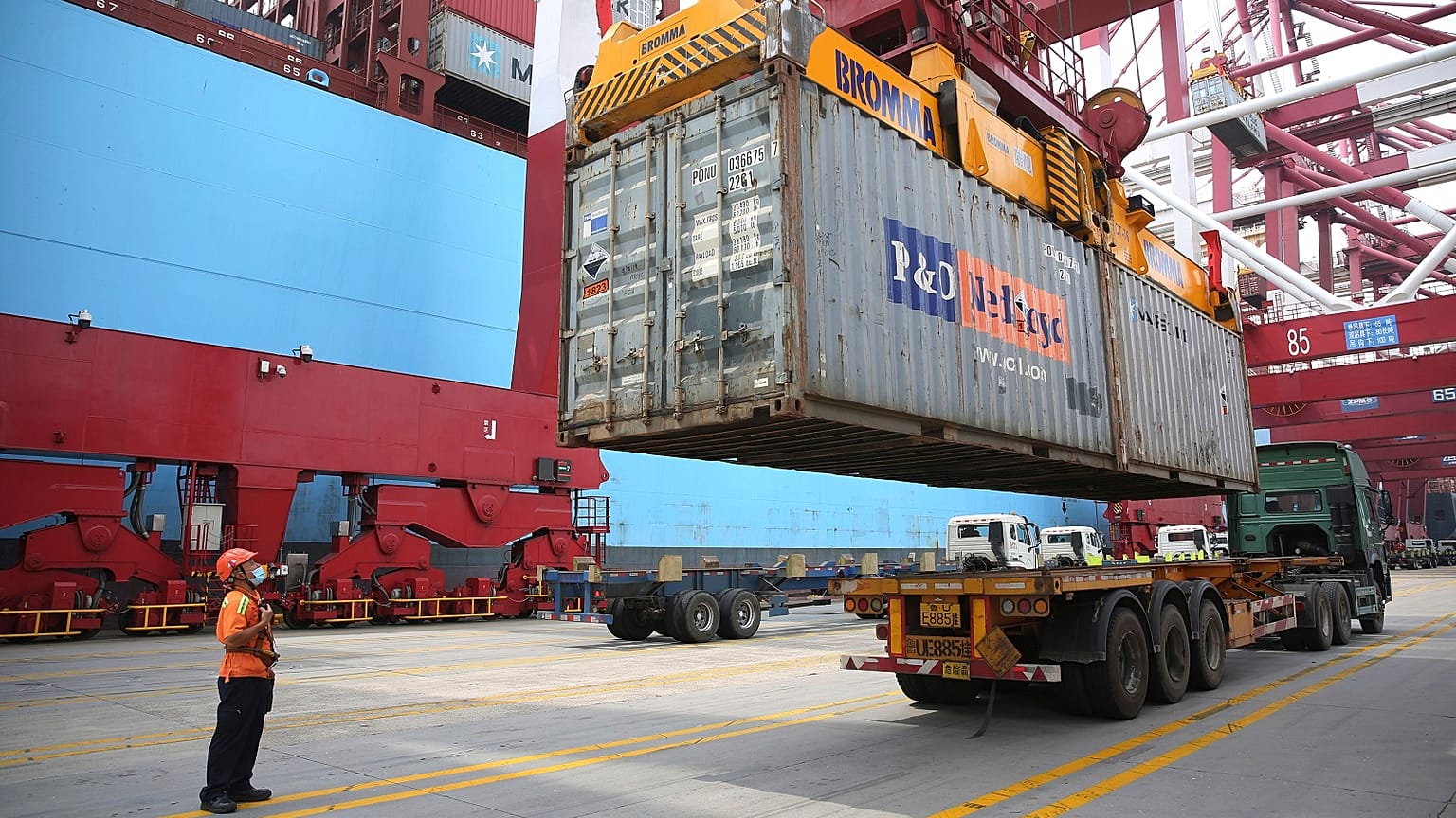 A worker wearing a face mask to protect against the new coronavirus guides the loading of a shipping container at a container port in Qingdao in eastern China.