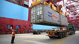 A worker wearing a face mask to protect against the new coronavirus guides the loading of a shipping container at a container port in Qingdao in eastern China.