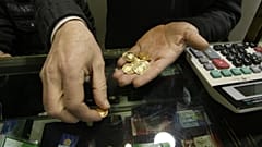 An Iranian goldsmith counts his gold coins at a gold market in the main old Bazaar of Tehran, Iran
