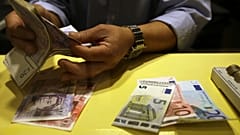 An employee counts British pounds and Euro notes at a currency exchange office