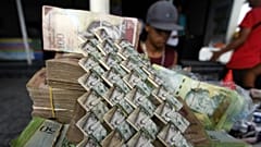 Venezuelan Bolivars are weaved together at a vendor's table selling art and bags made from the currency