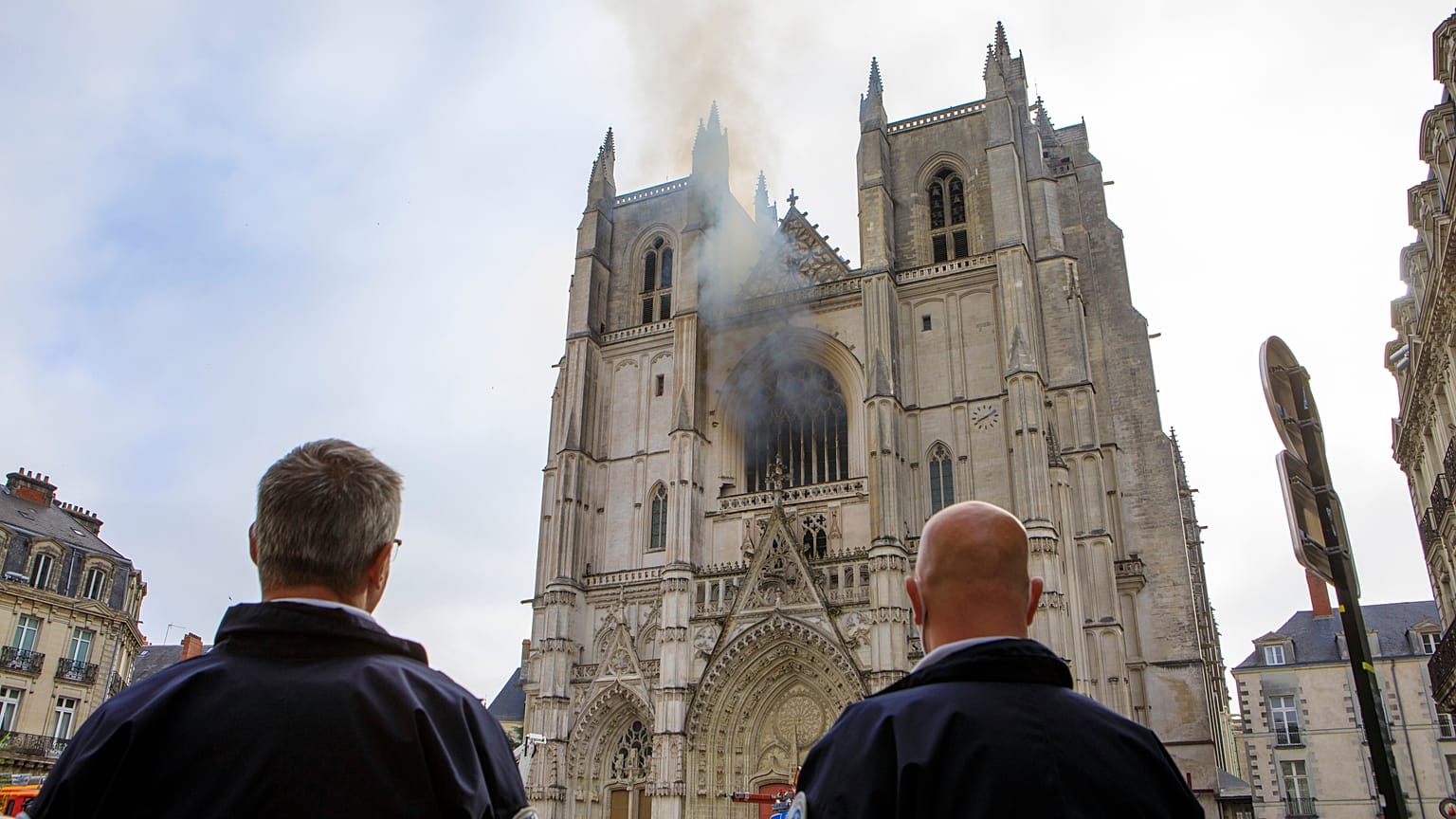 Des policiers observent la fumée qui se dégage de la cathédrale de Nantes, Samedi 18 juillet 2020