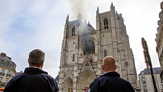 Des policiers observent la fumée qui se dégage de la cathédrale de Nantes, Samedi 18 juillet 2020