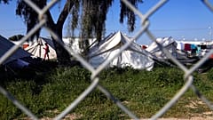 A migrant walks by the tents inside a refugee camp in Kokkinotrimithia outside of Nicosia, Cyprus, Tuesday, March 3, 2020.