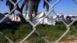 A migrant walks by the tents inside a refugee camp in Kokkinotrimithia outside of Nicosia, Cyprus, Tuesday, March 3, 2020.