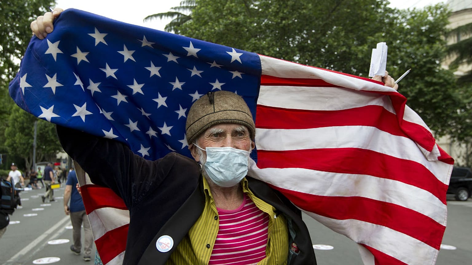 An elderly activist, wearing a face mask to protect against coronavirus, waves the US flag during a rally in Tbilisi, Georgia