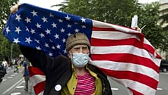 An elderly activist, wearing a face mask to protect against coronavirus, waves the US flag during a rally in Tbilisi, Georgia