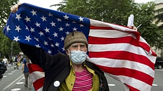 An elderly activist, wearing a face mask to protect against coronavirus, waves the US flag during a rally in Tbilisi, Georgia