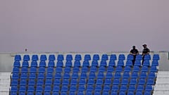 Gradas de un campo de fútbol sin aficionados y policías vigilando con mascarilla