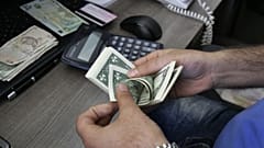 A currency exchange bureau worker counts U.S. dollars in downtown Tehran, Iran