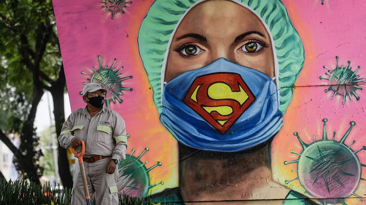 Un jardinero trabaja junto a un mural del artista urbano Applez, en Ciudad de México