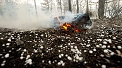 A log keeps burning as hail lies on the ground near Susanville, California. July 21, 2020 